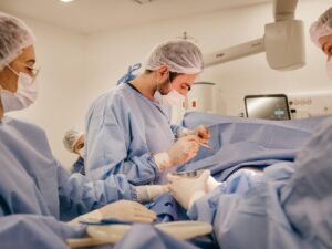 Surgeons and nurses collaborating during a surgical procedure wearing protective gear in a hospital operating room.